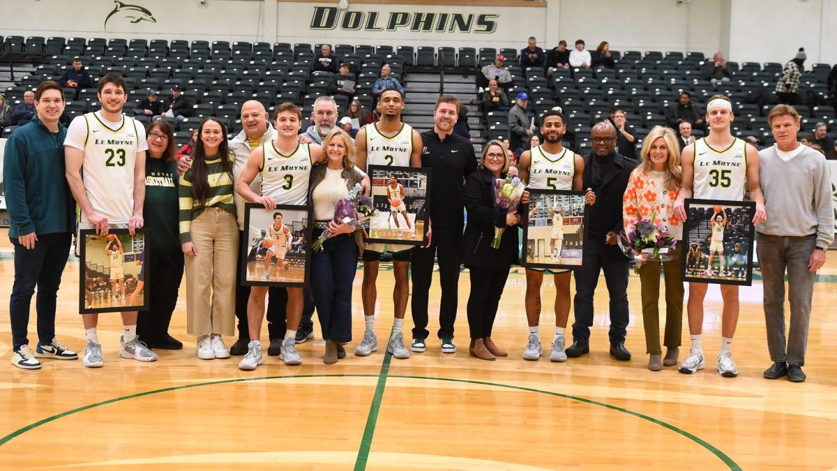 Le+Moyne+College+men%E2%80%99s+basketball+coach+is+surrounded+by+his+graduate+players+and+their+families%2C+in+a+ceremony+honoring+their+key+contributions.+Photo+courtesy+Greg+Wall+and+Le+Moyne+athletics.